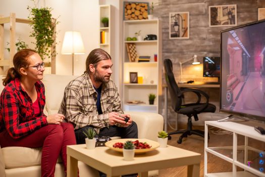 Couple playing video games on big screen TV in the living room late at night.