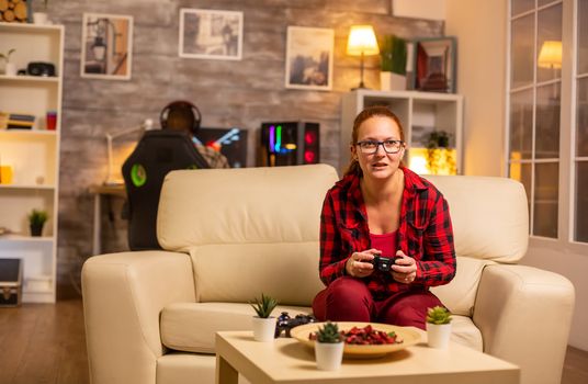 Woman gamer playing video games on the console in the living room late at night