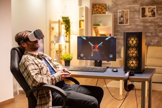 Professional gamer man using VR headset to play on powerful PC late at night in his living room