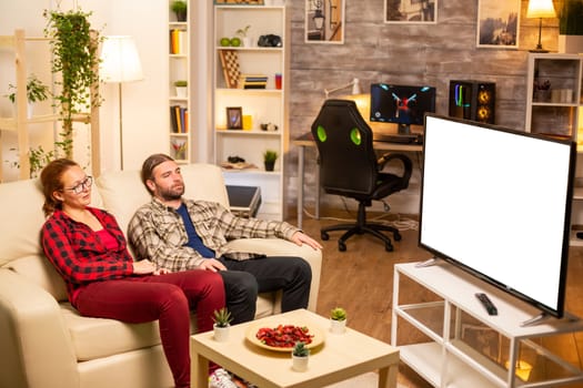 Couple looking at white isolated TV screen late at night in living room.