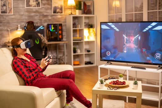 Woman gamer playing video games using a VR headset late at night in the living room