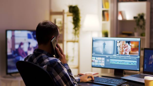 Content creator talking on the phone while working on a multimedia project using modern software for post production.