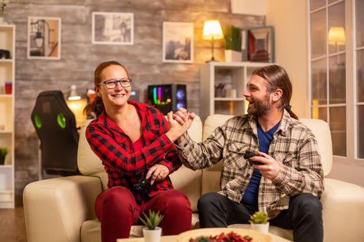 Gamers couple playing video games on the TV with wireless controllers in hands.