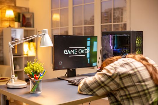 Professional male gamer playing on powerful PC and losing the game late at night in the living room