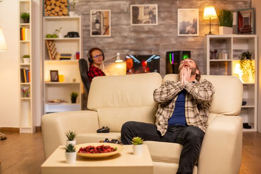 Angry and frustrated man video game player on the sofa late at night in the living room