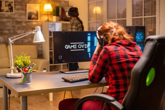Gamer woman losing at a video game playing late at night in the living room.
