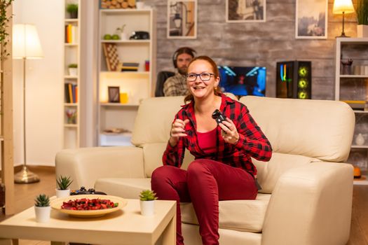 Woman gamer playing video games on the console in the living room late at night