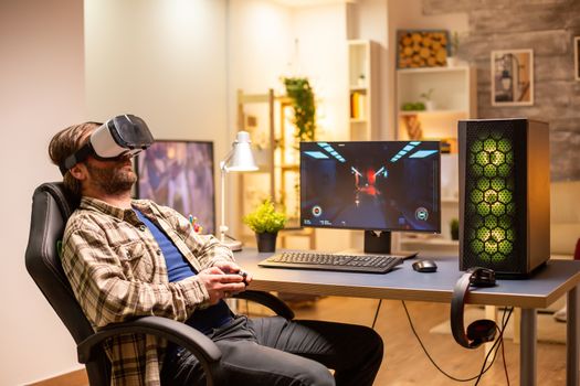 Professional gamer man using VR headset to play on powerful PC late at night in his living room