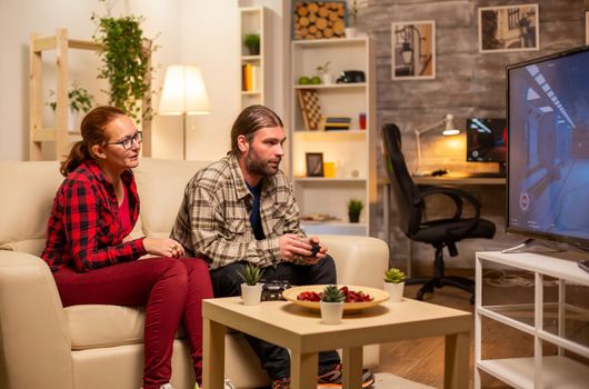 Couple playing video games on big screen TV in the living room late at night.