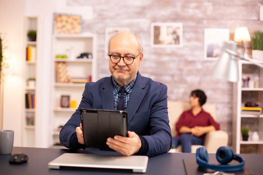 Senior man in his 60s using a modern digital tablet in his cozy home