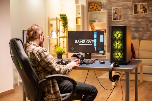 Man on his powerful PC computer in the living room late at night loosing a game.