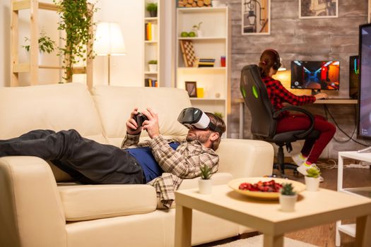 Man gamer using a VR headset to play video games in the living room late at night