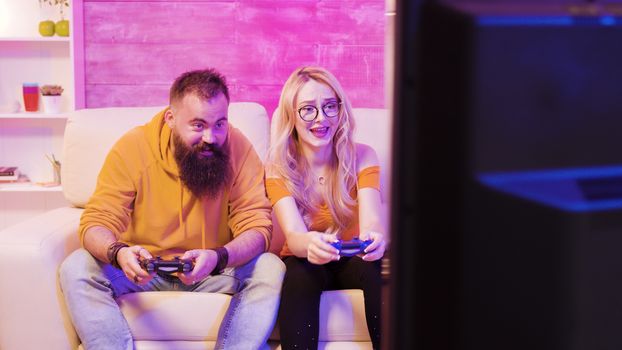 Upset young couple after losing while playing online video games using wireless controllers. Disappointment on their faces