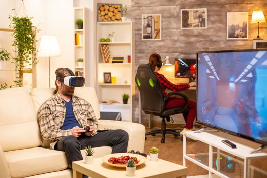 Man gamer using a VR headset to play video games in the living room late at night