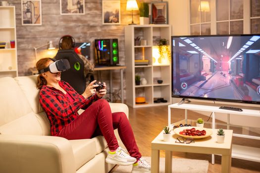 Woman gamer playing video games using a VR headset late at night in the living room