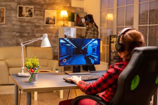 Professional video gamer female playing an online shooter game late night in the living room