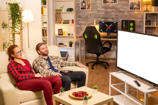 Couple looking at white isolated TV screen late at night in living room.