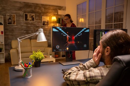 Back view of professional video gamer playing on powerful PC late at night in the living room.