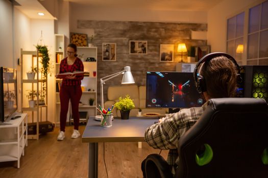 Back view of professional video gamer playing on powerful PC late at night in the living room.