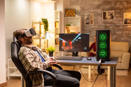 Professional gamer man using VR headset to play on powerful PC late at night in his living room