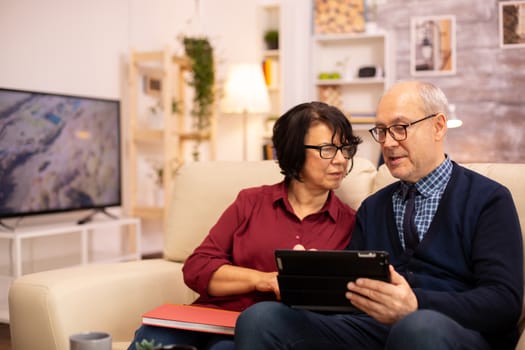 Beautiful old couple using a digital tablet to chat with their family. Elderly people using modern technology