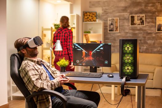 Professional gamer man using VR headset to play on powerful PC late at night in his living room