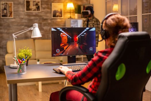 Professional video gamer female playing an online shooter game late night in the living room