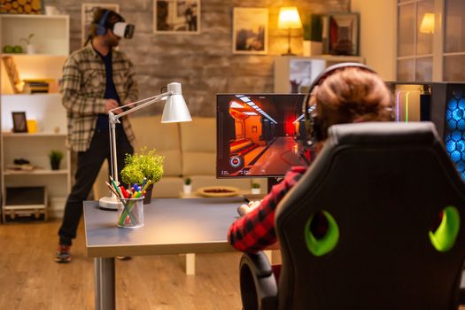 Professional video gamer female playing an online shooter game late night in the living room