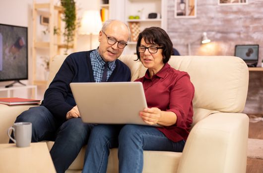 Elderly old couple using modern laptop to chat with their grandson. Grandmother and grandfather using modern technology