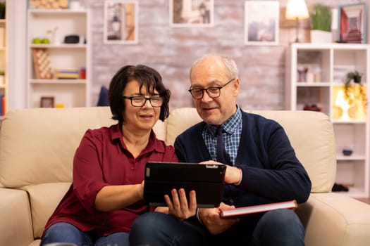 Beautiful old couple using a digital tablet to chat with their family. Elderly people using modern technology