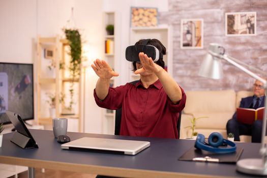 Old elderly woman using a VR virtual reality headset for the first time in her house. Concept of active elderly people using modern technology