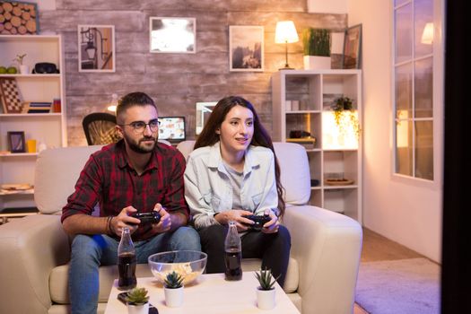 Boyfriend playing video games with his girlfriend on television using controllers.