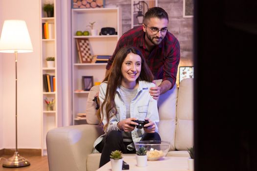 Photo of young couple playing video games on television at night.