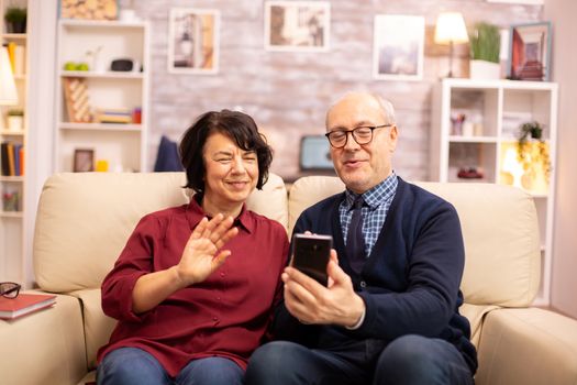 Old eldelry couple using a smartphone to talk with their family.