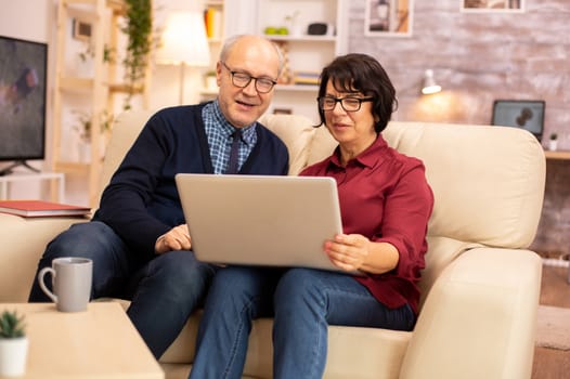 Elderly old couple using modern laptop to chat with their grandson. Grandmother and grandfather using modern technology