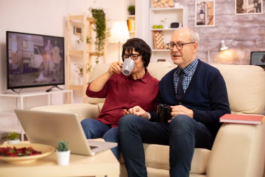 Elderly old couple using modern laptop to chat with their grandson. Grandmother and grandfather using modern technology