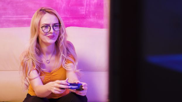 Beautiful blonde girl upset because she lost while playing video games in her room with colorful lights.
