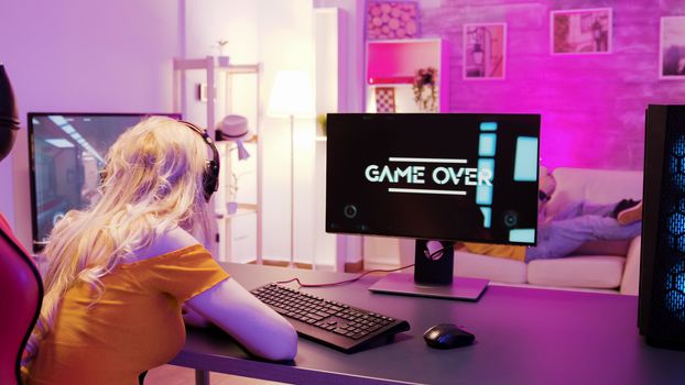 Sad blonde because she lost on a shooter game. Girl playing games and sitting on gaming chair.