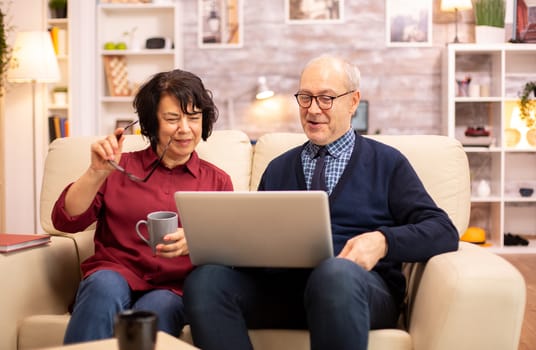 Elderly old couple using modern laptop to chat with their grandson. Grandmother and grandfather using modern technology