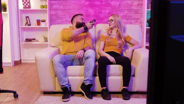Boyfriend wins against his girlfriend while playing video games using wireless controllers sitting on couch.