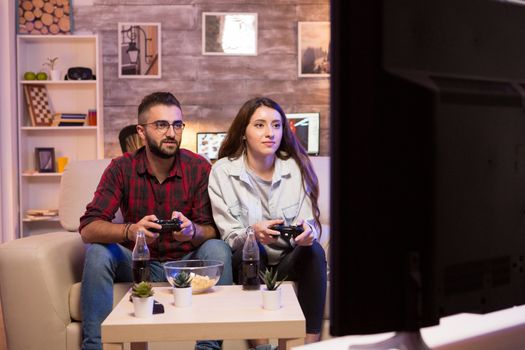 Boyfriend playing video games with his girlfriend on television using controllers.