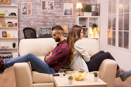 Couple sitting back to back on the couch ignoring each other. Relationship problems.
