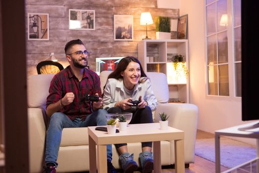 Happy young couple after winning at video games on television sitting on couch at night.