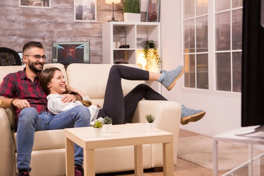 Beautiful young couple relaxing on sofa while watching a movie on tv.