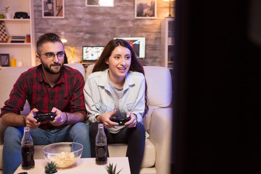 Concentrated young couple while playing video games on television. Couple sitting on couch.