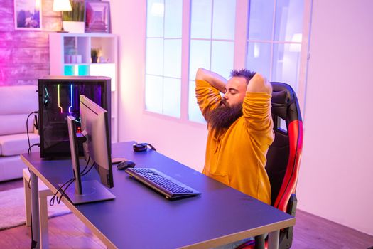 Caucasian bearded gamer preaparing himself for a sesion of video games in room full of neon lights