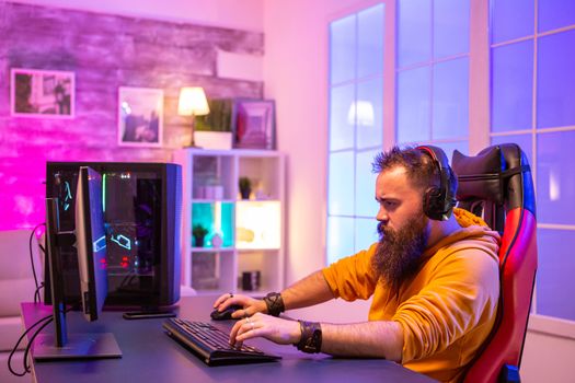 Professional EA sport gamer playing on powerful PC in room with neon lights