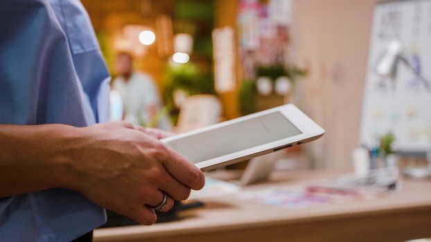 Woman designer holding a digital tablet PC in hands, close up shot. Loft office in the background