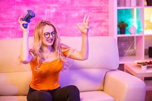 Beautiful blonde girl upset because she lost while playing video games in her room with colorful lights.