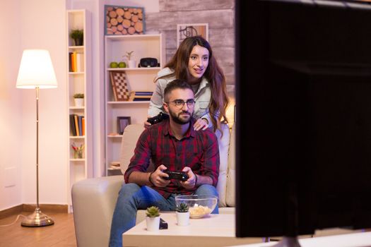 Photo of young couple playing video games on television at night.